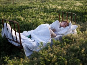 femme qui dort dans un lit dans un champ
